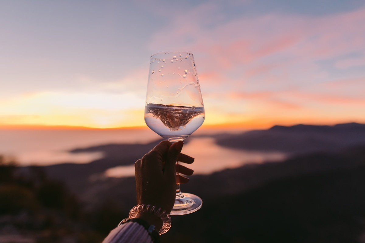 Copa de vino en viñedo griego viendo el atardecer