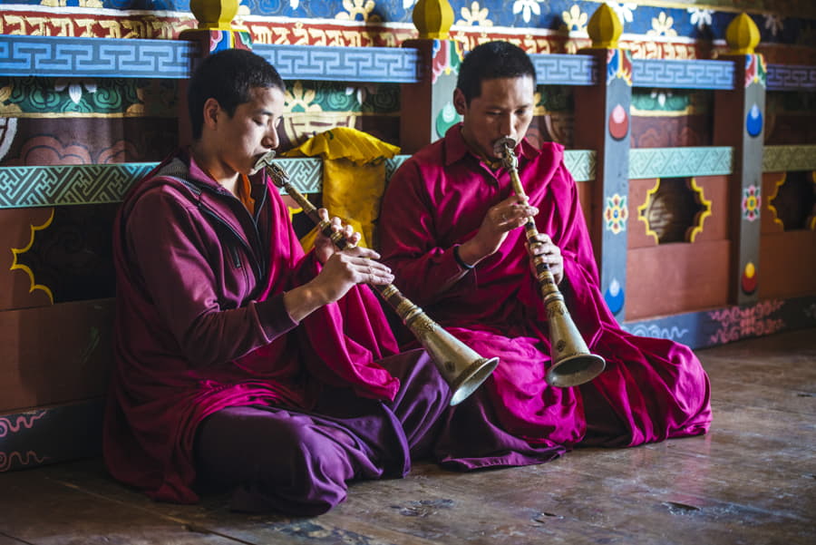 Monjes asiáticos tocando instrumentos en el suelo del templo