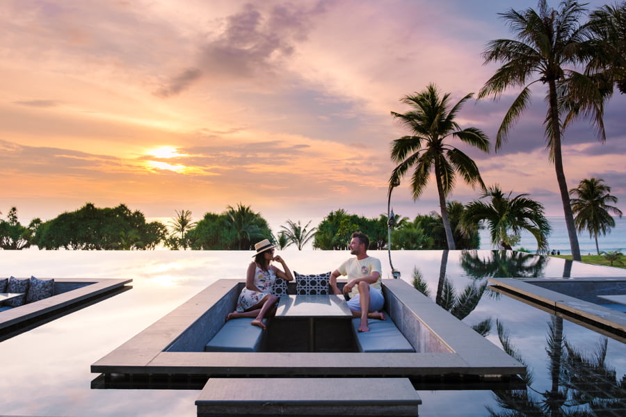 pareja viendo la puesta de sol en la piscina infinita de una villa de lujo