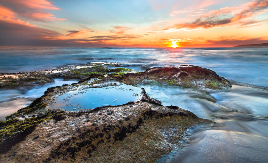 Larga exposición de las olas del océano que fluyen sobre marismas rocosas al atardecer en Johanna Beach, en el Parque Nacional Great Otway, Victoria, Australia.